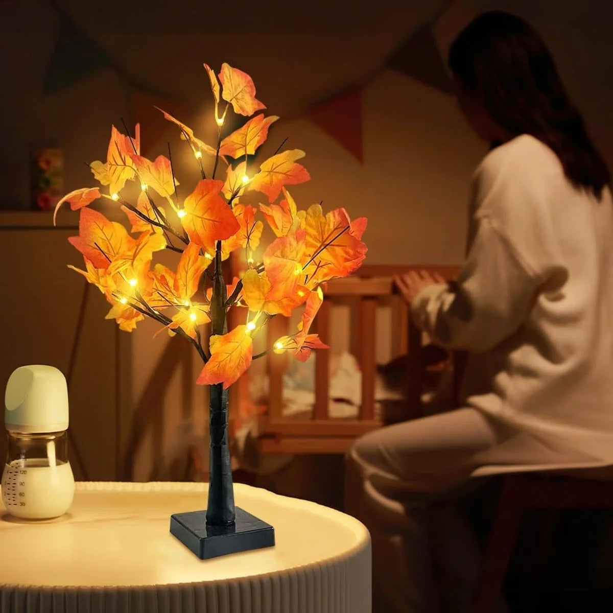 Une branche d'un arbre de bouleaux noirs artificiel avec un éclairage aux feuilles orange lumineuses repose sur une table.
