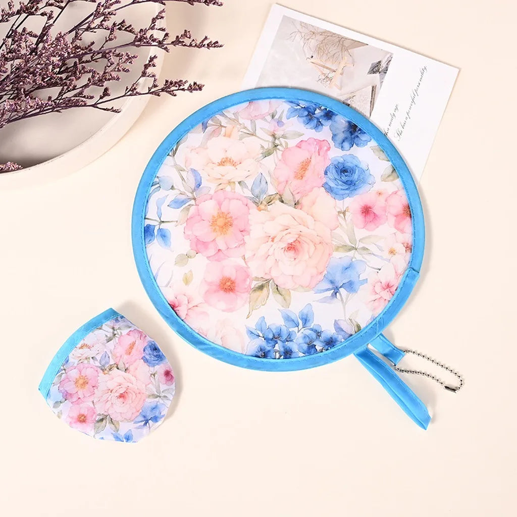 A blue fabric fan with a floral pattern is shown, along with a loose piece of the same fabric and a card.