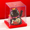 A black cat figurine with pink accents is displayed inside a clear red box.