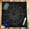 A black cloth featuring a white pentagram design and various astrological symbols on a wooden surface.