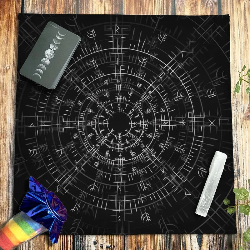A black cloth featuring a white pentagram design and various astrological symbols on a wooden surface.