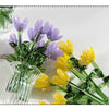 A bouquet of handmade glass flowers in shades of purple and yellow displayed in a clear glass vase.