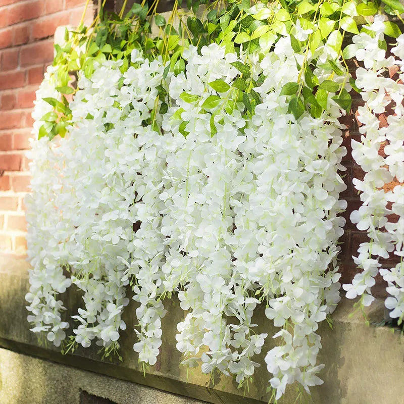 Cascade de fleurs artificielles de wisteria blanches drapées sur un mur de briques.