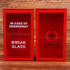 Dos cajas rojas etiquetadas como EN CASO DE EMERGENCIA BREAK GLASS e IM NOTFALL, para romper
