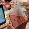 A hand holds a double-sided laminated pink magnet featuring a face design.