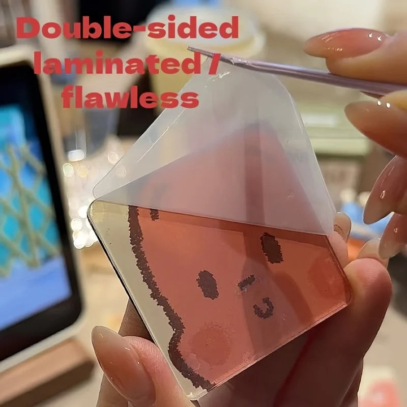 A hand holds a double-sided laminated pink magnet featuring a face design.