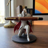 A 3D printed knight figurine holding a wooden pen, displayed on a dark circular base.
