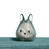 A clear glass figurine shaped like a rabbit with long ears, resting on a teal surface.