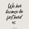 A black script quote from 1 John 4:19 on a light gray background.