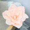 A large, soft peach colored foam rose flower displayed on a wooden surface.