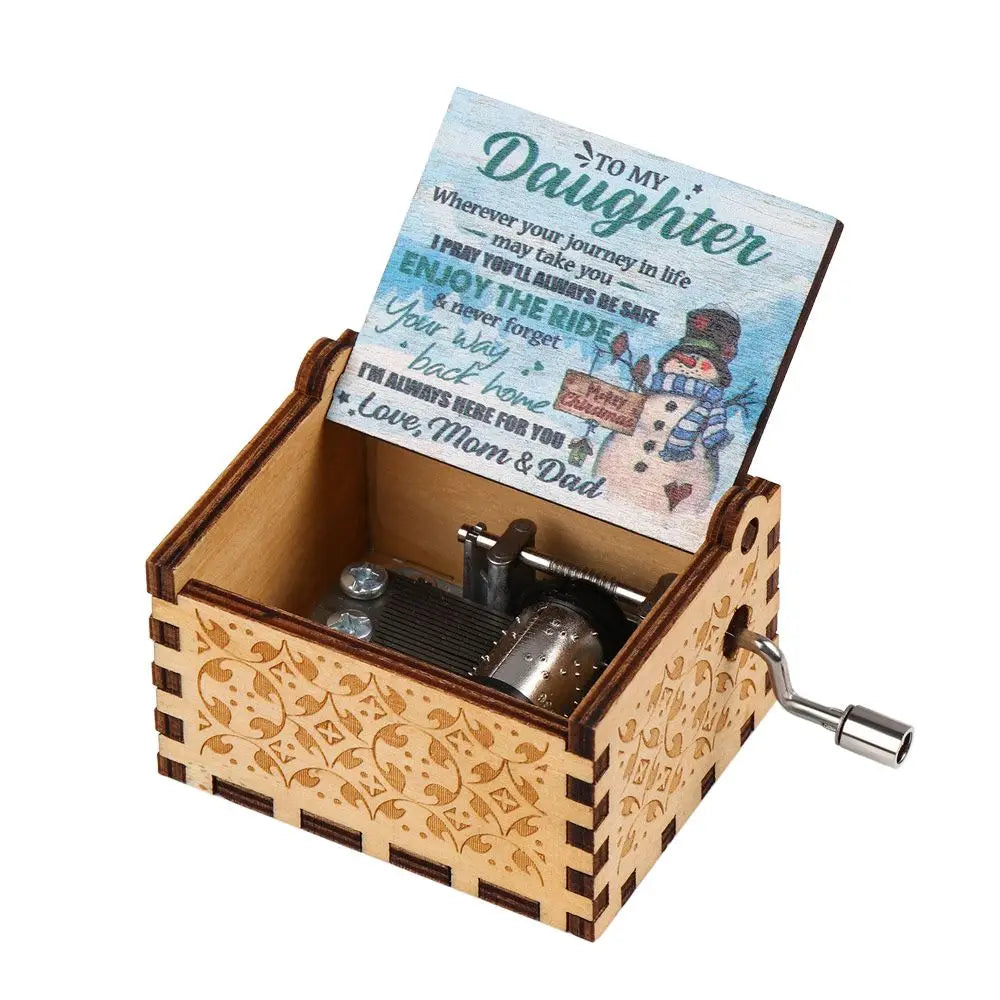 A vintage hand-cranked wooden music box with a lid featuring a message to a daughter