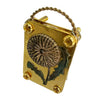 A small brass metal flower press kit with a dried flower pressed inside and a wire loop for hanging.