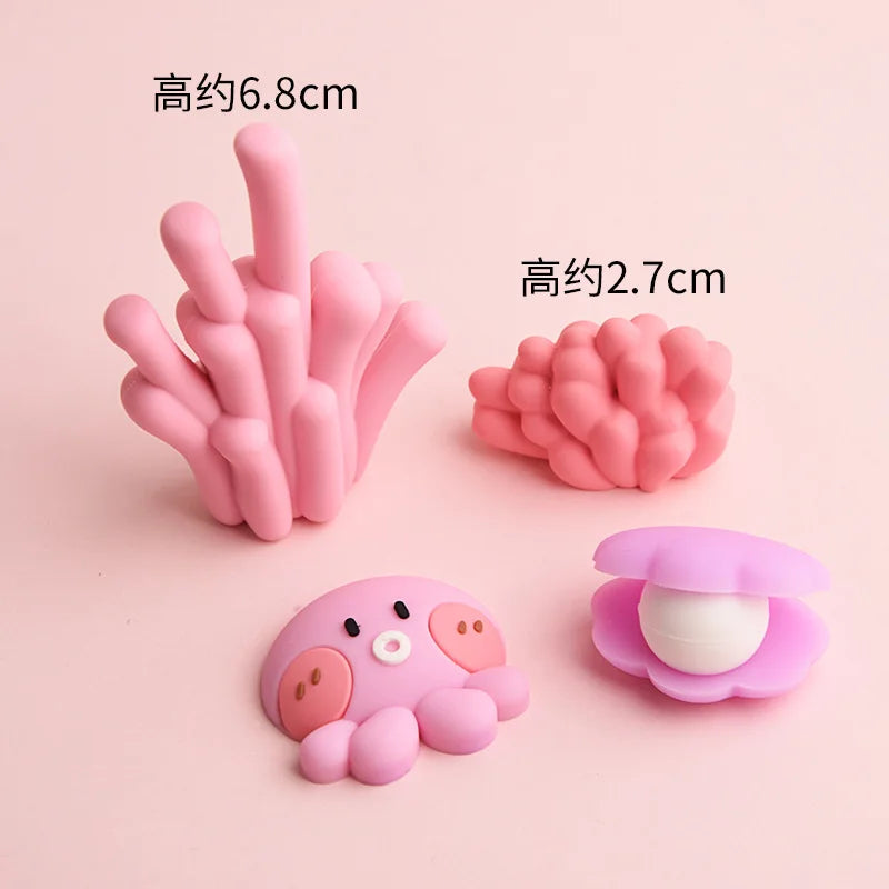 A set of pink silicone ocean animal cake toppers including a crab, turtle, octopus, whale, starfish, and shell decor.