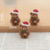 A set of festive Christmas resin decor featuring two brown teddy bears wearing red Santa hats and green plaid scarves.