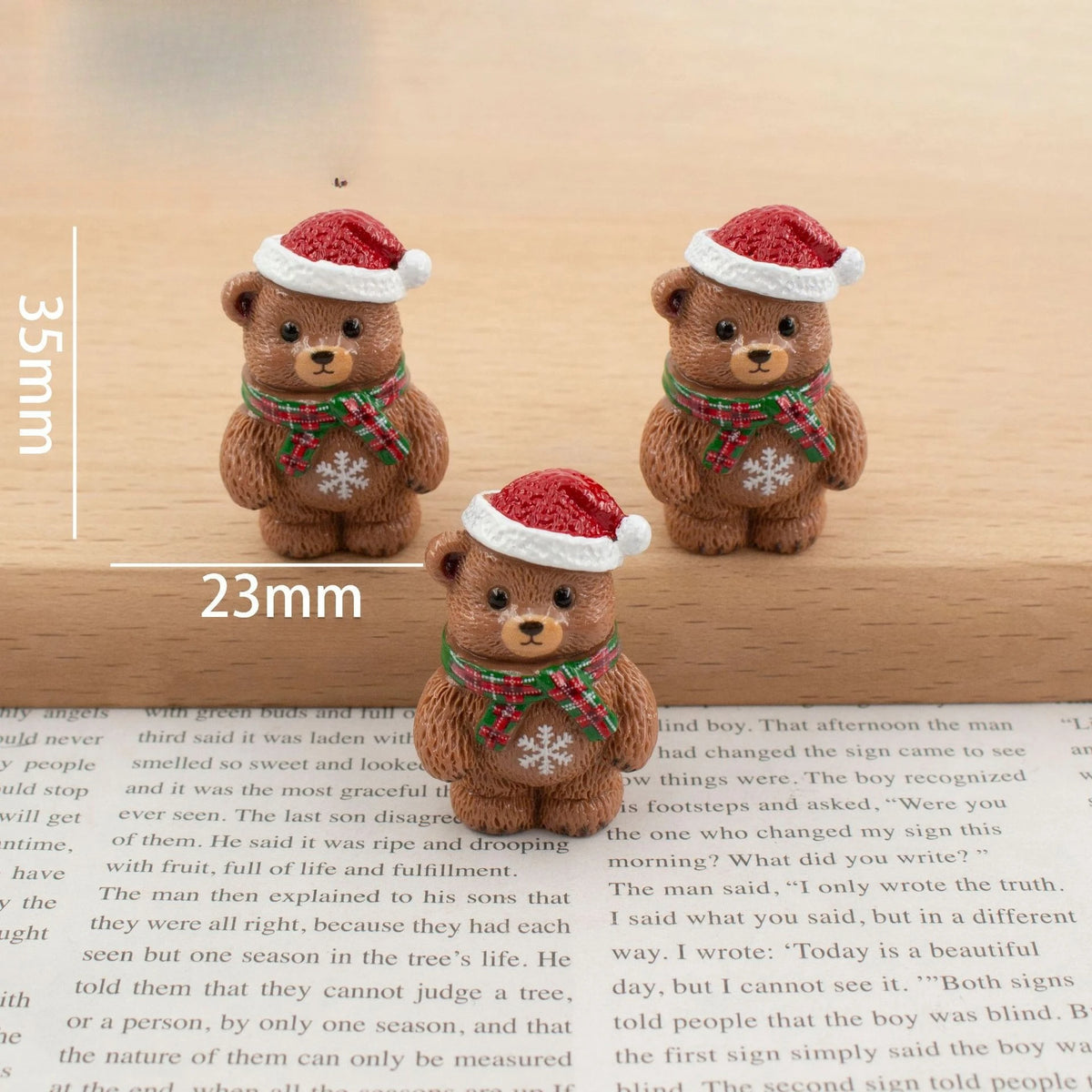 A set of festive Christmas resin decor featuring two brown teddy bears wearing red Santa hats and green plaid scarves.