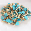 A pile of mini wooden photo clips shaped like hearts in light blue and teal colors.