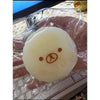 A yellow, squishy toy shaped like a bear with a simple face, packaged in clear plastic.