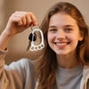 A smiling girl holds up a stainless steel keychain with multiple loops and keys.