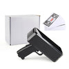 A black money shooter toy gun is shown next to its packaging and some fake dollar bills.