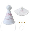 White decorative birthday hat with pink ribbon and pom-pom, along with small gold embellishments.