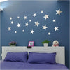 A wall decorated with silver and gold star-shaped acrylic mirror decor on a blue wall above a white fireplace mantel.