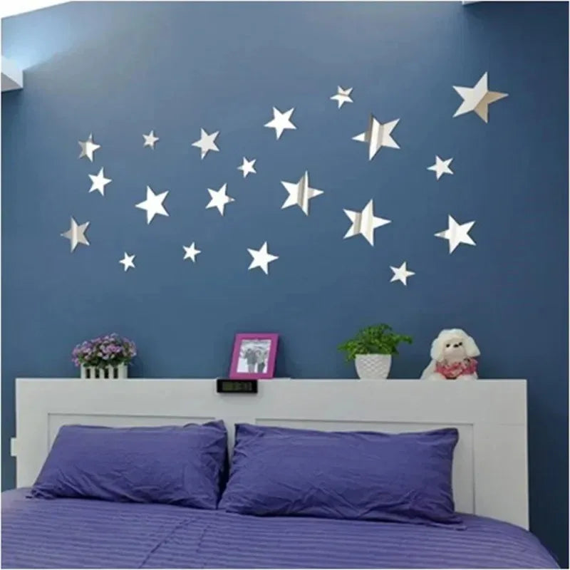 A wall decorated with silver and gold star-shaped acrylic mirror decor on a blue wall above a white fireplace mantel.