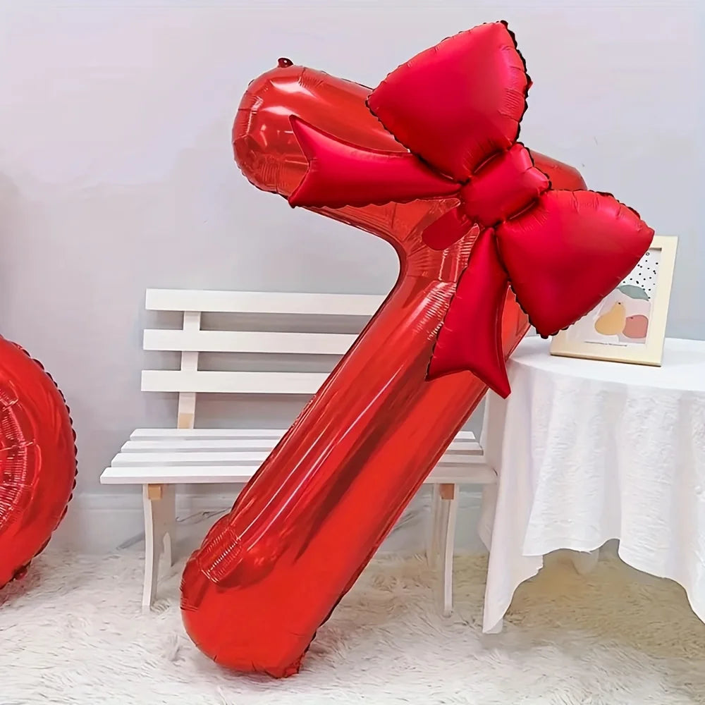 A large red foil number balloon shaped like the number 1, featuring a matching red bow, displayed on a white table.