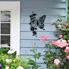 Black metal art of an Art Nouveau butterfly silhouette mounted on a light blue wooden siding.