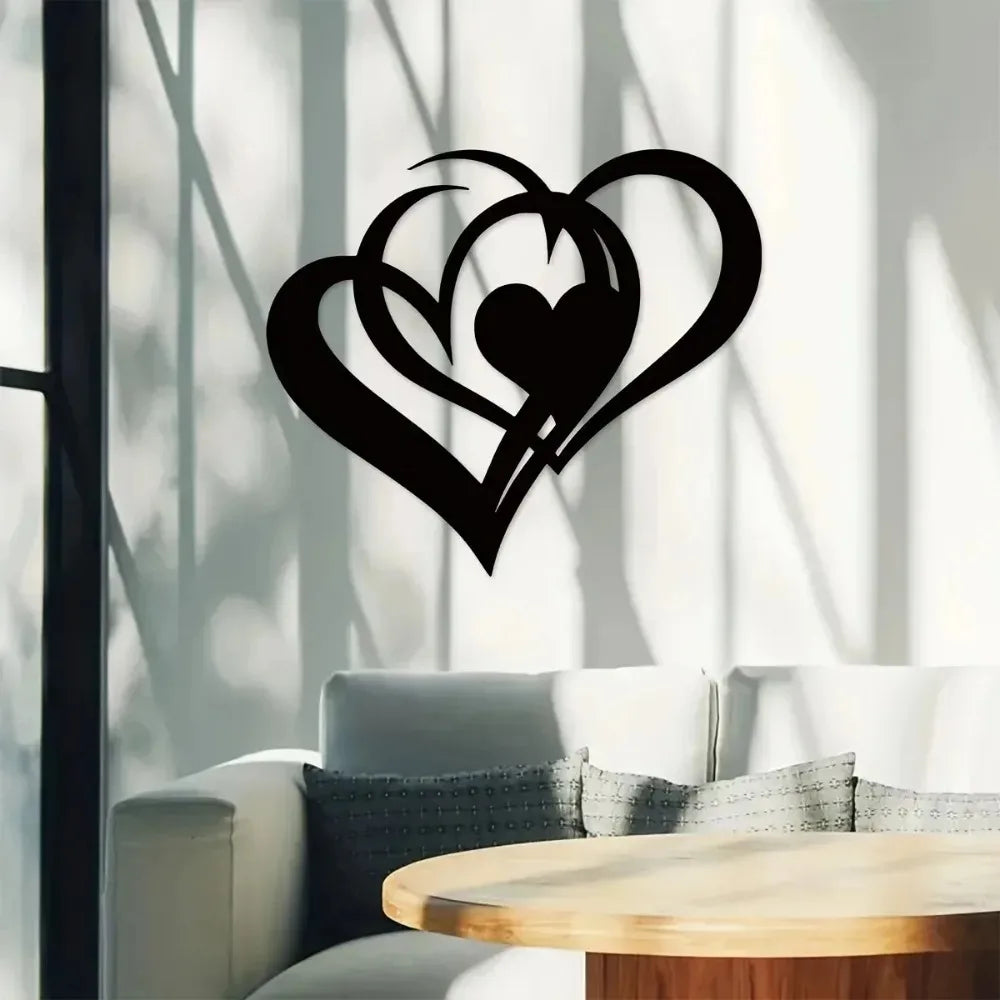 Black silhouette of two intertwined hearts on a light wall with sunlit shadows.