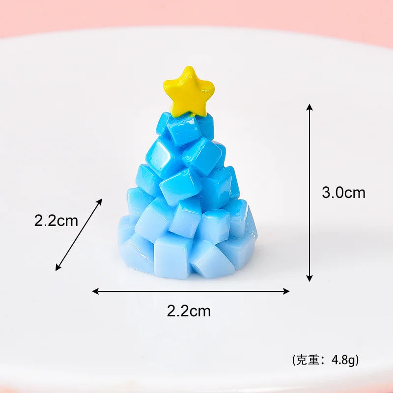 A small, light blue resin Christmas tree charm with a yellow star topper, displayed on a white surface.