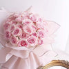 A bouquet of pink roses wrapped in decorative flower wrapping paper with gold edges.