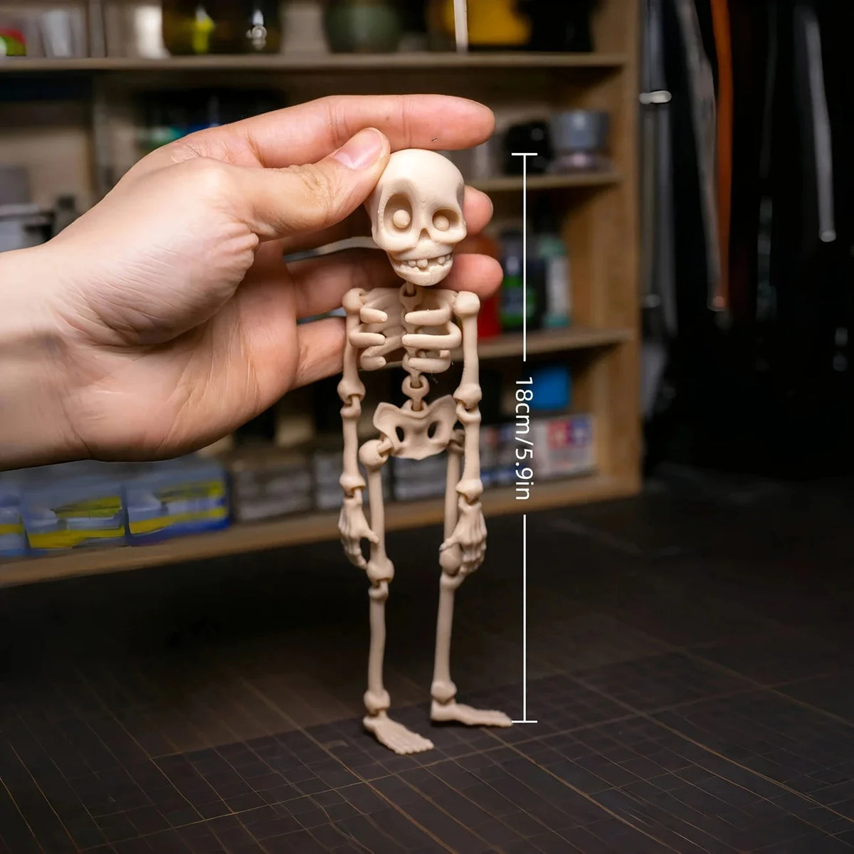 A hand holds a realistic skull skeleton model used for kitchen decor and refrigerator magnets.