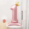 A pink foil number balloon shaped like the number one with a gold crown on top