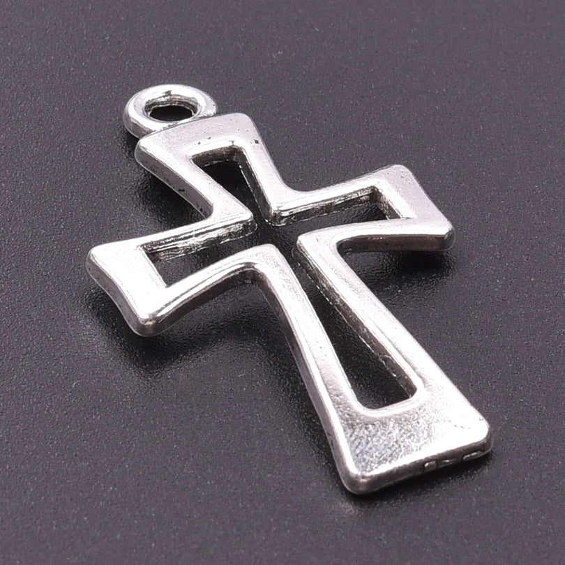 A silver antique cross charm with a bail, displayed on a dark gray background.