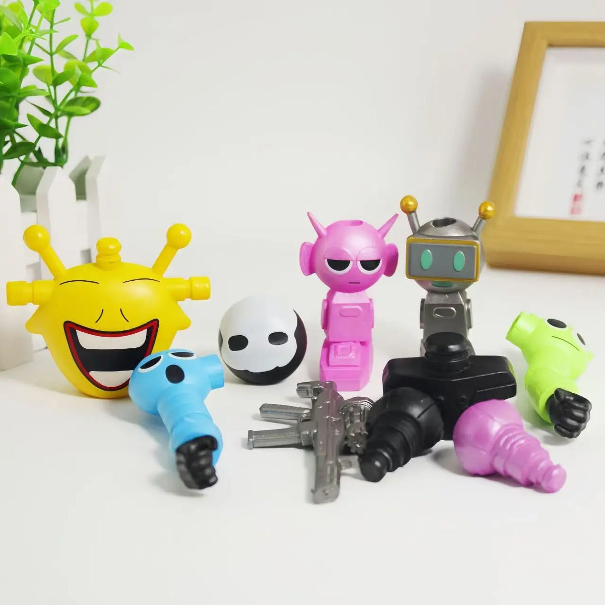 A collection of colorful robot joint models and toys including yellow, pink, and silver figures on a white surface.