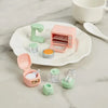 A set of pink and mint green realistic kitchen appliance dollhouse accessories including a grinder, mortar, and various small