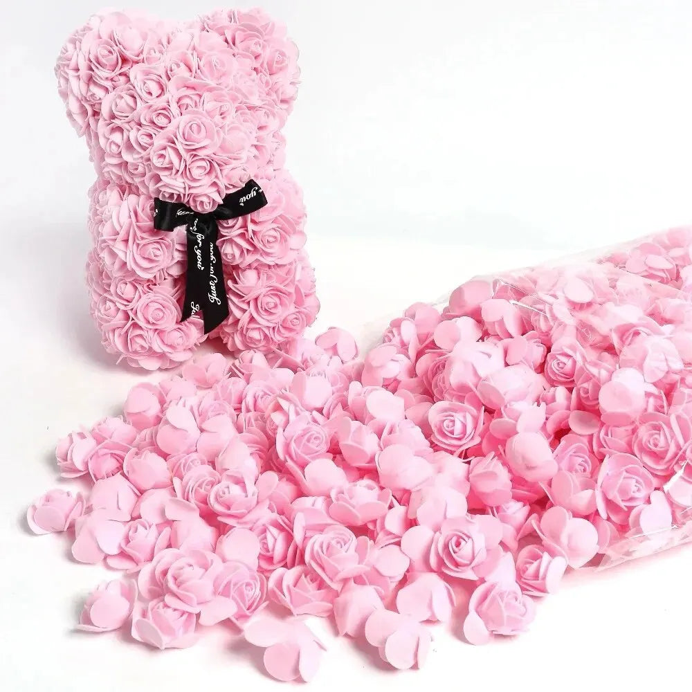 A pink artificial rose bouquet with a black ribbon and a loose pile of pink rose petals.