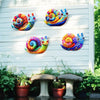 Colorful metal snail wall art featuring vibrant spiral designs displayed on a white wooden siding.