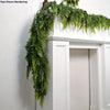 Extra long pine vine wreath draped over a white mantelpiece