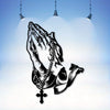 Black silhouette of praying hands with a cross, displayed against a light blue background under hanging lights.