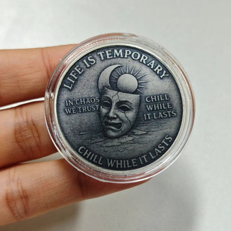 A clear coin with a dark engraving featuring a skull and sun, surrounded by text about life being temporary and chilling whil