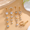 A set of five gold tone butterfly and flower belly rings displayed on a light beige surface.