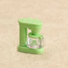 A light green kitchen appliance dollhouse accessory featuring a clear glass component and a plastic handle.