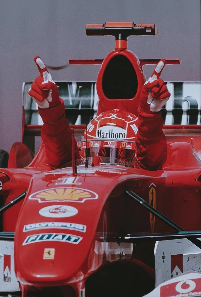 A close-up of a red Formula 1 racing car cockpit with a driver's hands and helmet visible.