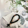 A handmade black 33-knot Orthodox prayer rope with a wooden cross charm resting on a silver plate.