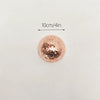 A round, rose gold mosaic disco ball decor mounted on a wall, with a 10cm/4in scale indicator.