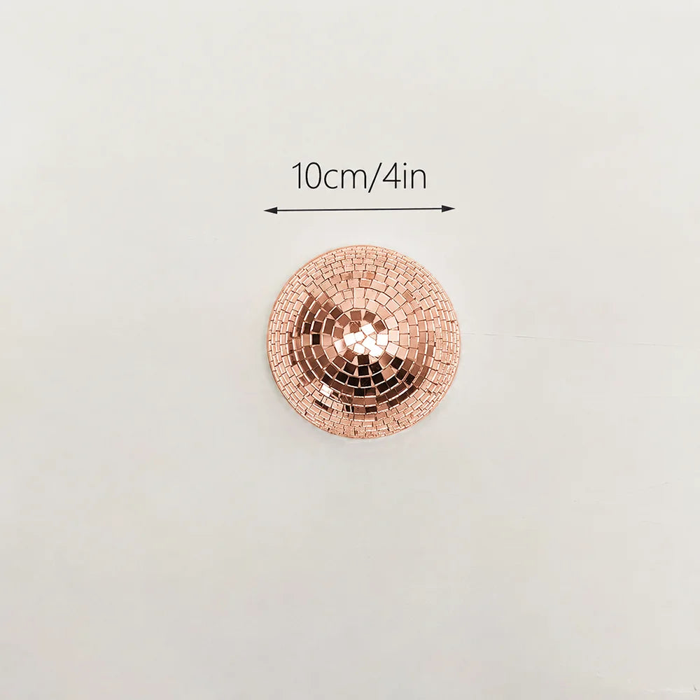 A round, rose gold mosaic disco ball decor mounted on a wall, with a 10cm/4in scale indicator.