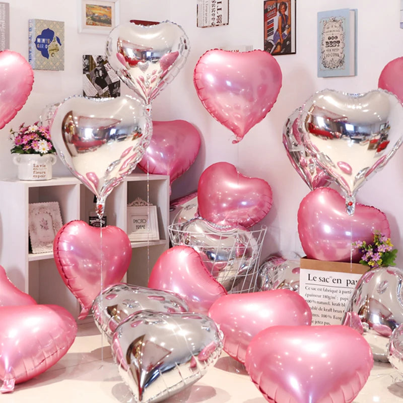 A collection of pink and silver heart-shaped foil balloons displayed on a white shelf.