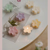 A collection of handmade soy wax flower tea light candles in various pastel colors and shapes arranged on a white surface.