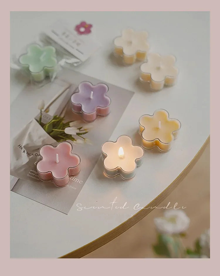 A collection of handmade soy wax flower tea light candles in various pastel colors and shapes arranged on a white surface.